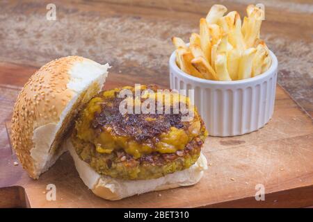 Kichererbsen Burger mit veganem Cheddar über einem Holzbrett Stockfoto