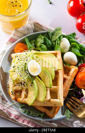 Frühstückszeit. Waffeln mit Salat, Ei, Saft und Avocados zum Frühstück. Blick von oben. Stockfoto