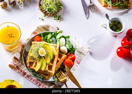 Frühstückszeit. Waffeln mit Salat, Ei, Saft und Avocados zum Frühstück. Blick von oben. Stockfoto