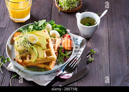 Frühstückszeit. Waffeln mit Salat, Ei, Saft und Avocados zum Frühstück. Blick von oben. Stockfoto