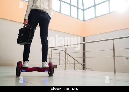 Der junge Geschäftsmann reitet auf einem gyroboard Stockfoto