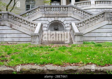 Detaillierte Steintreppen mit einem abgehauenen Brunnen, der von einem Grasenhof zu einem abanonierten Anwesen führt Stockfoto