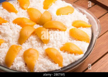 Geriebenes Kokosnussdessert mit Pfirsich über einem Holztisch Stockfoto