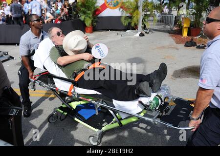 MIAMI, FL - AUGUST 13: Ein Mitt Romney Unterstützer wird von Sanitätern weggerollt, während republikanischer Präsidentschaftskandidat Mitt Romney während einer Kampagne spricht Stockfoto