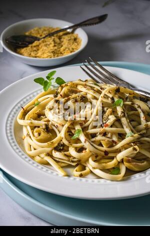 Veganes Nudelgericht. Fettuccine mit Pesto, grünen Oliven, frischem Thymian und Nährhefe. Stockfoto