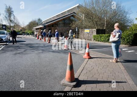 Schlange warten, um in Booth's Supermarkt in der Yorkshire Dales Marktstadt Settle, North Yorkshire zu bekommen. Der Supermarkt hält die 2 Meter soziale Distanz außen und eine begrenzte Anzahl von Käufern ist in einem Moment erlaubt. Quelle: John Bentley/Alamy Live News Stockfoto