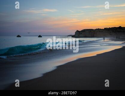 Portugal, Algarve, die besten Strände von Portimao, Praia da Rocha, Sonnenuntergang über dem Atlantischen Ozean, Menschen an der Küste des abendlichen Atlantischen Ozeans, Seagu Stockfoto