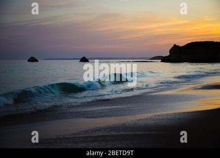 Portugal, Algarve, die besten Strände von Portimao, Praia da Rocha, lila Sonnenuntergang über den blauen goldenen Wellen des Atlantischen Ozeans, Abendansicht des cl Stockfoto