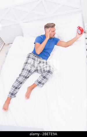 Kann es nicht ertragen. Müde unglücklicher Mann im Bett. Mann leidet unter Kopfschmerzen. Schrecklich laute Geräusche. Schlaflosigkeit und Schlafstörungen. Tägliche Routine. Stressigen Mann aufwachen Schalten Sie den Wecker. Zeit zum Aufwachen. Stockfoto