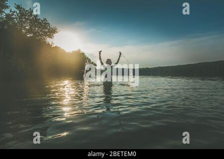 Nettes Mädchen mit langen blonden Haaren Spaß im Teich in Magie goldene Stunde Zeit Stockfoto