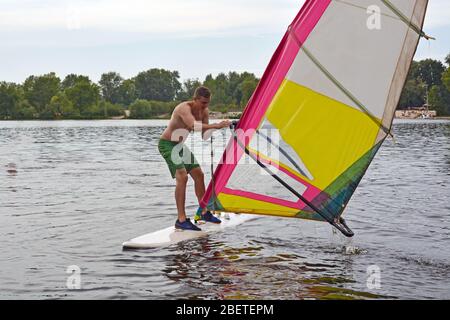 Man steht auf dem Board im Wasser Windsurfen Stockfoto