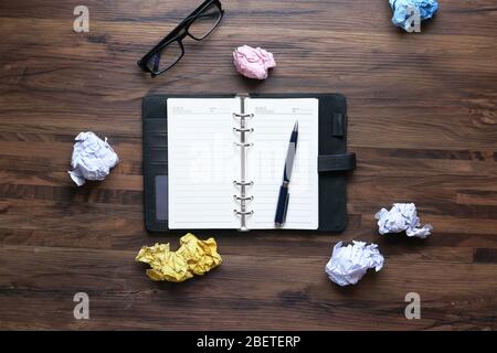 Hohe Winkelansicht der zerknittern Papierkugel und Notizblock auf dem Tisch Stockfoto