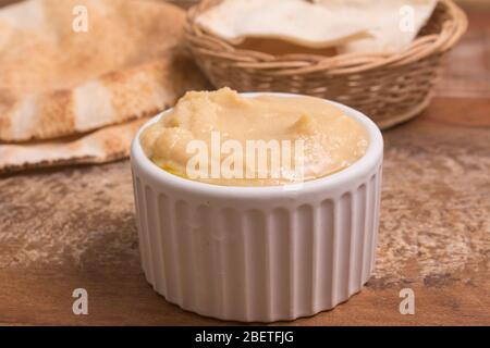 Kichererbsen Hummus in einer Schüssel und arabisches Brot über einem Holztisch Stockfoto