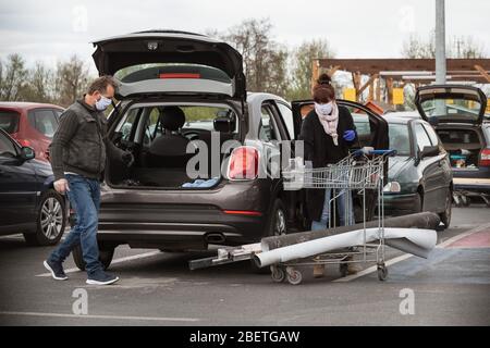 LUBIN, POLEN - 14. APRIL 2020. Mann und Frau laden Einkäufe aus einem Supermarkt in einem Gebäude in den Kofferraum eines Autos. Stockfoto