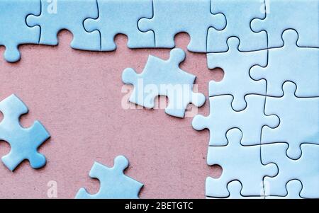 Verbundene Stücke von blauen ein-Farb-Puzzle mit drei getrennten Stücke auf rosa Hintergrund. Nahaufnahme. Stockfoto