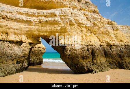 Gelber Kalksteinbogen auf goldenem Sandstrand Praia da Rocha der Atlantikküste mit türkisfarbenem Wasser in der Nähe der Stadt Portimao, Portugal Stockfoto