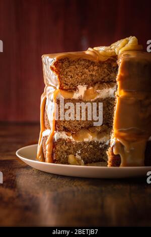 Geburtstagstorte innen mit Biskuitschichten, Joghurtfüllung und Äpfeln, mit Karamellglasur. Lagenkuchen in Scheiben geschnitten. Festliches Dessert mit Äpfeln. Stockfoto