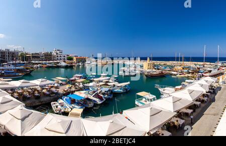 Panoramablick von der alten Burg von Marina Hafen und Hafen mit Yachten in Kyrenia Girne Stadt gegen blauen Himmel und Berge, Nordzypern Stockfoto