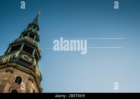 Turm der Kirche des Heiligen Petrus vor dem blauen Himmel mit den Spuren der Flugzeuge, Riga, Lettland Stockfoto