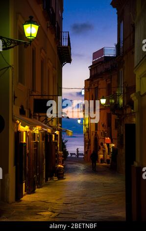 Nachts Abend Straßen mit hellen Laternen Lampen auf Gebäuden mit Balkonen, Silhouette des Wanderers und bunten Himmel mit Wolken auf Hintergrund, TR Stockfoto