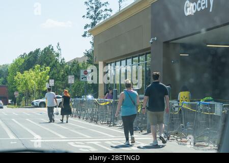 Kennesaw, GA / USA - 04/05/20: Walmart Linie vor dem Geschäft mit maskierten Menschen üben soziale Distanz 6 Fuß auseinander während Covid-19 Corona Viru Stockfoto