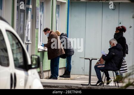 Sofia, Bulgarien. 15. April 2020. Arbeitslose, die Schutzmaske tragen, warten und füllen Formulare auf spontanen sozialen Distanzierungstabellen vor einem lokalen Arbeitszentrum der Abteilung für Sozialschutz aus. Die Arbeitslosigkeit im Land ist auf 7% wegen des Pandemischen Coronavirus Covid gestiegen - 19 nach Jahren stabil niedriger Raten bei rund 3.5%. Stockfoto