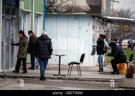 Sofia, Bulgarien. 15. April 2020. Arbeitslose, die Schutzmaske tragen, warten und füllen Formulare auf spontanen sozialen Distanzierungstabellen vor einem lokalen Arbeitszentrum der Abteilung für Sozialschutz aus. Die Arbeitslosigkeit im Land ist auf 7% wegen des Pandemischen Coronavirus Covid gestiegen - 19 nach Jahren stabil niedriger Raten bei rund 3.5%. Stockfoto