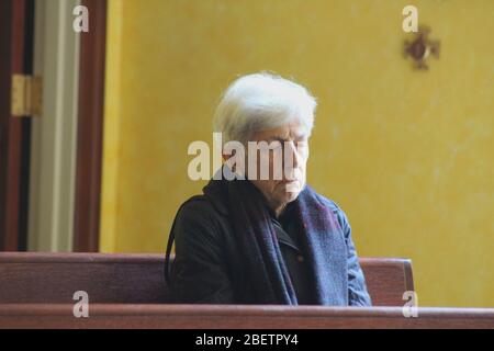 New York, New York, USA. April 2020. Diese Frau betet schweigend, die Augen geschlossen, Ã‚Â der Handtasche auf ihrer Schulter, allein auf einer Holzbank in der Chapel of the Sacred Hearts in Manhattan sitzend. Dieses religiöse Gebäude, eines der wenigen unter der Pandemie in New York geöffneten, liegt in der Nähe der Krankenhäuser NYU und Bellevue, die mit voller Geschwindigkeit gegen das Coronavirus kämpfen. Quelle: Marie Le BLE/ZUMA Wire/Alamy Live News Stockfoto