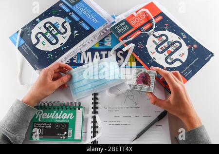 Ein Konzeptbild zur Verwendung mit GCSE-Untersuchungen, die aufgrund eines Coronavirus abgebrochen werden. Student mit Revisionsbüchern neben einer PSA-Gesichtsmaske. Stockfoto