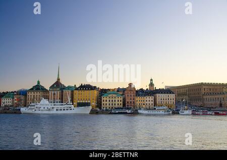 Altes historisches Stadtviertel Gamla Stan mit traditionellen typischen Gebäuden mit bunten Mauern, Königspalast auf Stadsholmen Insel, weißes Schiff auf Stockfoto