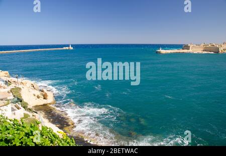 Blick auf den Hafen Eingang und alte mittelalterliche Ricasoli East Breakwater mit Leuchtturm und Fort Ricasoli von Valletta, Malta Stockfoto