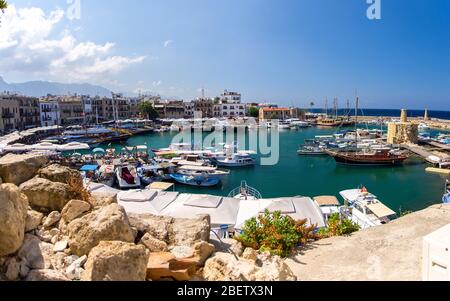 Panoramablick von der alten Burg von Marina Hafen und Hafen mit Yachten in Kyrenia Girne Stadt gegen blauen Himmel und Berge, Nordzypern Stockfoto