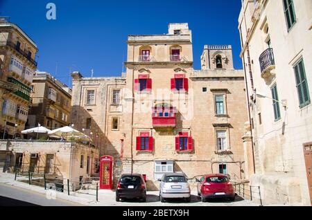 Blick auf gelbe Gebäude mit roten Balkonen und Fenstern auf die Srteets von Valletta, Malta Stockfoto