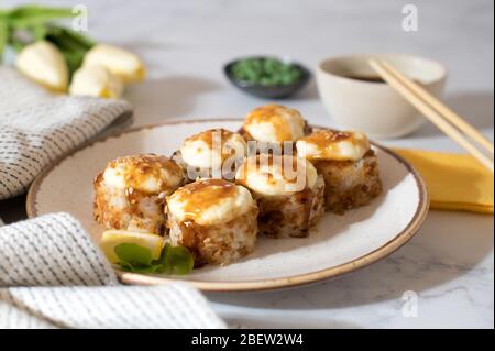 Sushi-Brötchen mit Unagi-Sauce auf weißem Teller serviert. Hellgrauer Hintergrund Stockfoto