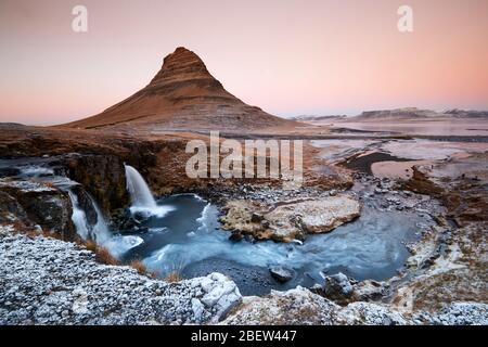 Kirkjufellsfoss, Island - 27. Nov 2019: Lange Belichtung während Sonnenuntergang über dem Kirkjufellsfoss Wasserfall mit Kirkjufell Berg im Hintergrund Stockfoto