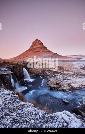 Kirkjufellsfoss, Island - 27. Nov 2019: Lange Belichtung während Sonnenuntergang über dem Kirkjufellsfoss Wasserfall mit Kirkjufell Berg im Hintergrund Stockfoto