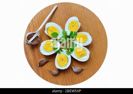 Gekochte Eier mit Rucola-Spigs und Knoblauchzehen auf einem Schneidebrett Stockfoto