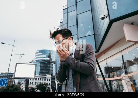 Kranker Mann hustet und niest auf der Straße der Stadt. Stockfoto