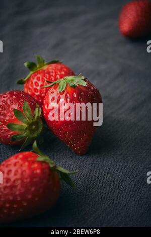 Nahaufnahme von frischen Erdbeeren mit Blättern und selektivem Fokus auf dunklem Hintergrund. Gesundes Lifestyle-Konzept. Stockfoto