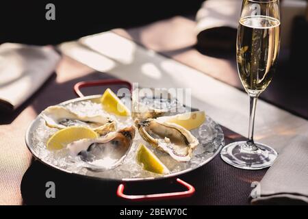 Teller mit Austern, Zitrone und Eis und einem Glas Champagner Stockfoto