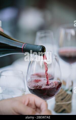 Rotwein wird aus der Flasche in Glaadd gegossen Stockfoto