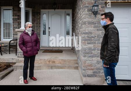 Mann und ältere Frau sprechen während des Covid 19 mit Gesichtsmasken. Stockfoto