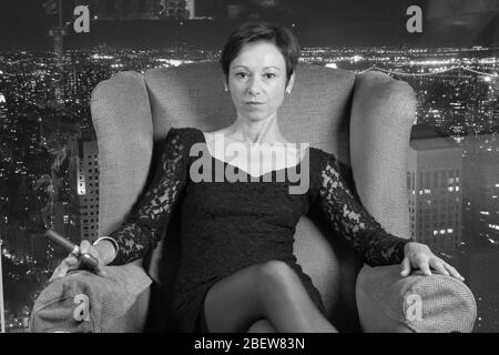 Diese Frau ist der Chef, der auf ihrem Trainer sitzt und eine Zigarre raucht Stockfoto