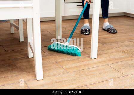 Menschen, Hausarbeit, Reinigung und Housekeeping Konzept - Nahaufnahme von Frauen Beine mit Besen fegen Boden zu Hause. Stockfoto