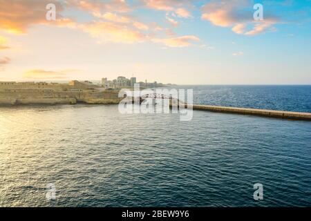 Die St. Elmo Brücke, eine Bogenbrücke unter einem bunten Sonnenuntergang Himmel in der Dämmerung im Valletta Grand Harbour der Mittelmeerinsel Malta. Stockfoto