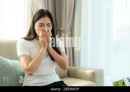 Asian Woman krank und traurig mit Niesen an der Nase und kaltem Husten auf Gewebepapier, weil Influenza und schwache oder Virusbakterien von Staubwetter oder Rauch Stockfoto
