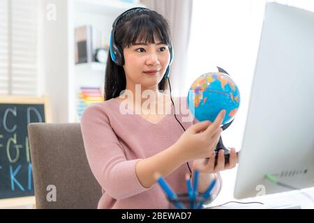 Asian Woman Teaching Geography per Videokonferenz E-Learning und fröhliche Grundschüler mit Blick auf Globe, Homeschooling und dist Stockfoto