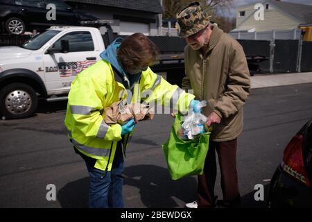Chelsea, Massachusetts, USA. April 2020. Chelsea, Massachusetts, ist der am stärksten betroffenen Bereich des Staates während COVID-19, Corona Virus. Eine überwiegend lateinamerikanische Gemeinschaft, die sich den Luxus sozialer Distanz nicht leisten kann. Die Stadt hat eine Bevölkerung von 40,000 Menschen in einem 2 Quadratmeilen Radius. 80% der Bevölkerung gelten als wichtige Arbeitskräfte, wie Supermarktmitarbeiter, Transitmitarbeiter usw. das Chelsea-Schulsystem verteilt täglich Frühstück und Mittagessen an Bedürftige. Ein älterer Mann sammelt Nahrung. Kredit: Allison Dinner/ZUMA Wire/Alamy Live News Stockfoto