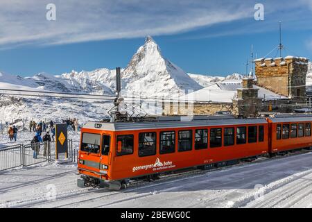 Gornergrat, Zermatt, Schweiz - 12. November 2019: Rote Seilbahn auf der Schneerbahn an der Bergstation mit Hintergrund des Matterhorn-Gipfels in w Stockfoto