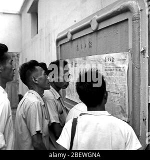 1964 nach dem Erfolg der ersten Atombombe Chinas lasen die Bürger von Guangzhou Zeitungen auf der Straße Stockfoto